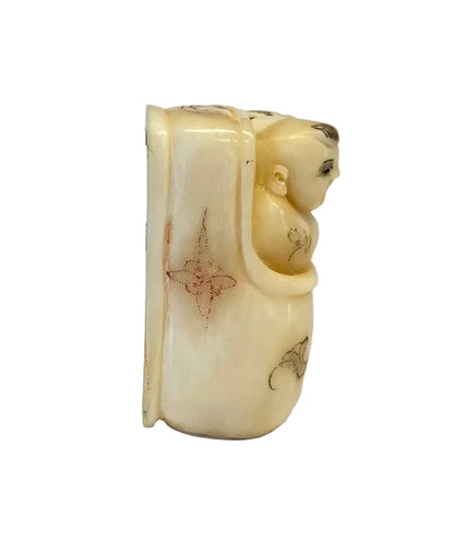 פסלון נטסקה (Netsuke) יפני עתיק: תינוק צוחק בעריסה | עצם מגולפת | חתום
