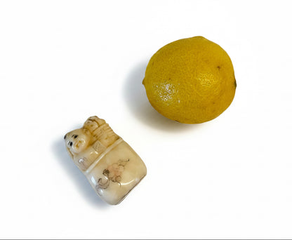 פסלון נטסקה (Netsuke) יפני עתיק: תינוק צוחק בעריסה | עצם מגולפת | חתום